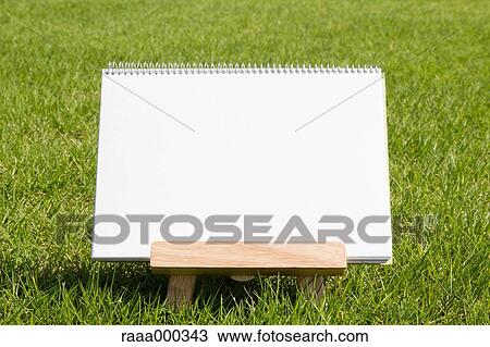 Stock Image - Empty sketchbook on grassland. Fotosearch