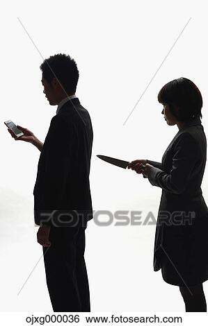 Stock Photograph - Japanese businesswoman holding kitchen knife against colleague. Fotosearch