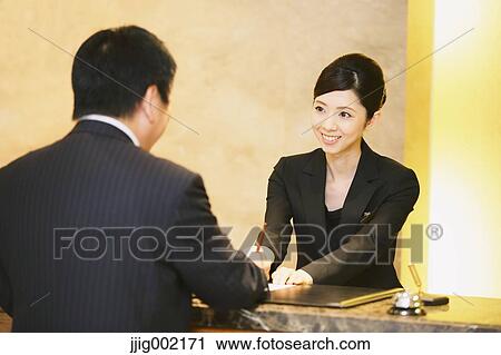 Stock Image - Japanese female hotel concierge dealing with a customer. Fotosearch