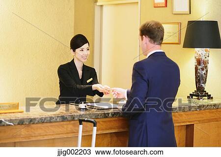 Stock Image - Japanese female hotel concierge dealing with a customer. Fotosearch