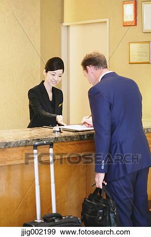 Stock Photo - Japanese female hotel concierge dealing with a customer. Fotosearch
