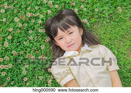 Stock Image - Japanese kid laying on grass in a park. Fotosearch