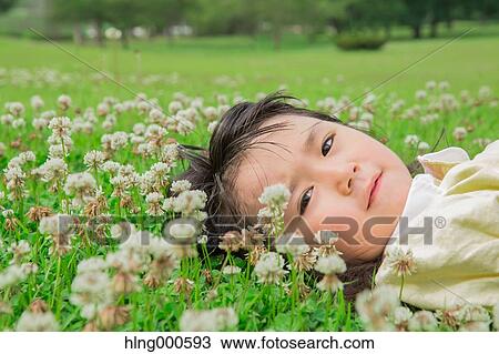 Stock Image - Japanese kid laying on grass in a park. Fotosearch