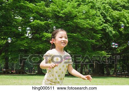 Japanese kid playing with soap bubbles in a park View Large Photo Image Stock Image - Japanese kid playing with soap bubbles in a park. Fotosearch