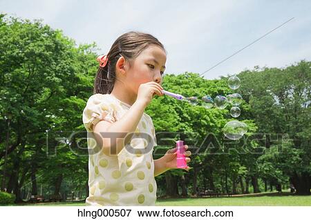 Japanese kid playing with soap bubbles in a park View Large Photo Image Stock Photo - Japanese kid playing with soap bubbles in a park. Fotosearch