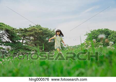 Stock Photograph - Japanese kid playing with soap bubbles in a park. Fotosearch