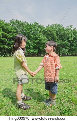 Stock Image - Japanese kid shaking hands in a park. Fotosearch