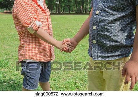 Stock Image - Japanese kid shaking hands in a park. Fotosearch