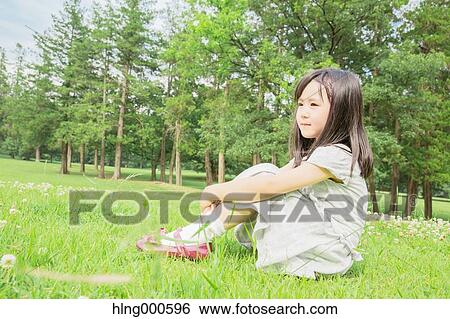 Stock Photograph - Japanese kid sitting on grass in a park. Fotosearch