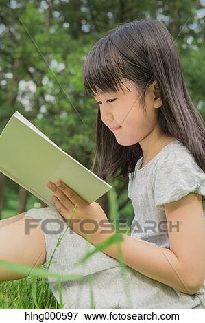 Japanese kid sitting on grass with a book in a park View Large Photo Image Stock Photo - Japanese kid sitting on grass with a book in a park. Fotosearch