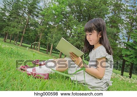 Japanese kid sitting on grass with a book in a park View Large Photo Image Stock Photo - Japanese kid sitting on grass with a book in a park. Fotosearch