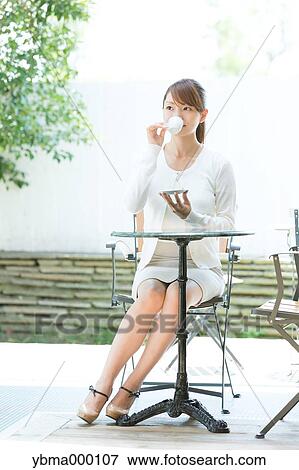 Attractive young girl having coffee outside View Large Photo Image Stock Photo - Attractive young girl having coffee outside. Fotosearch