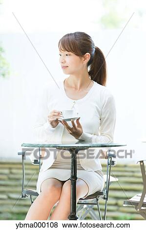 Attractive young girl having coffee outside View Large Photo Image Stock Photo - Attractive young girl having coffee outside. Fotosearch