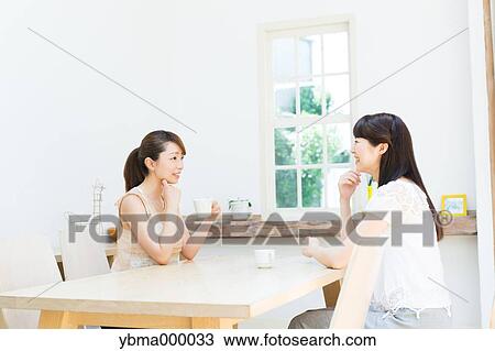 Attractive young girls chatting over a cup of coffee View Large Photo Image Stock Image - Attractive young girls chatting over a cup of coffee. Fotosearch