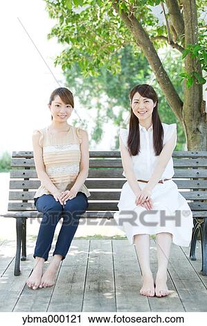 Attractive young girls sitting in a park View Large Photo Image Stock Image - Attractive young girls sitting in a park. Fotosearch