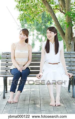 Attractive young girls sitting in a park View Large Photo Image Stock Image - Attractive young girls sitting in a park. Fotosearch