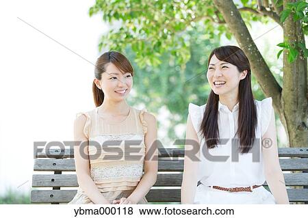 Attractive young girls sitting in a park View Large Photo Image Stock Photo - Attractive young girls sitting in a park. Fotosearch