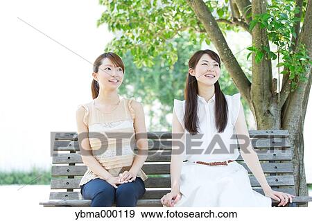 Attractive young girls sitting in a park View Large Photo Image Stock Photo - Attractive young girls sitting in a park. Fotosearch