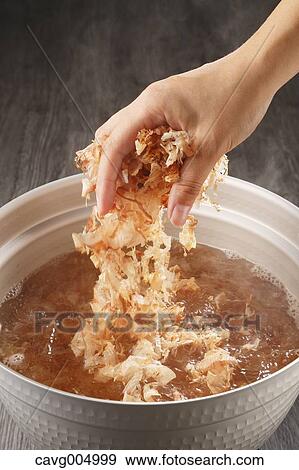 Stock Photo - Young Japanese girl adding Katsuobushi to soup. Fotosearch