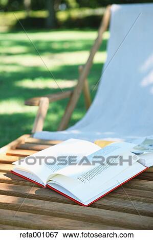 Stock Photo - Book on deck chair in a city park. Fotosearch