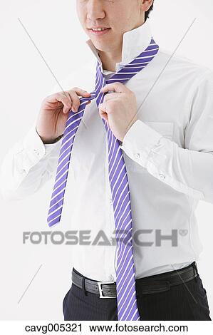 Stock Image - Businessman tying a necktie. Fotosearch
