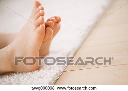 Stock Photo - Close up of elementary age girl feet on a white carpet. Fotosearch
