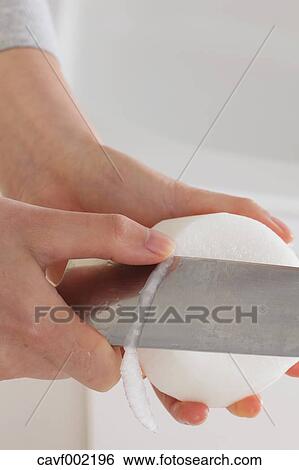 Stock Photograph - Close up of woman's hands peeling radish with a kitchen knife. Fotosearch