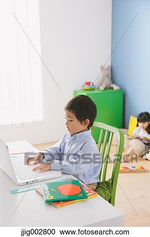 Elementary age boy doing his homework at his desk with his sister reading on the floor in the background View Large Photo Image Stock Image - Elementary age boy doing his homework at his desk with his sister reading on the floor in the background. Fotosearch