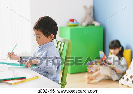 Elementary age boy doing his homework at his desk with his sister reading on the floor in the background View Large Photo Image Stock Photograph - Elementary age boy doing his homework at his desk with his sister reading on the floor in the background. Fotosearch