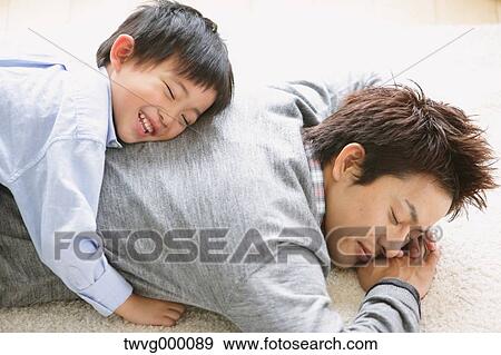 Elementary age boy laying on his fathers back and smiling with closed eyes View Large Photo Image Stock Photo - Elementary age boy laying on his fathers back and smiling with closed eyes. Fotosearch