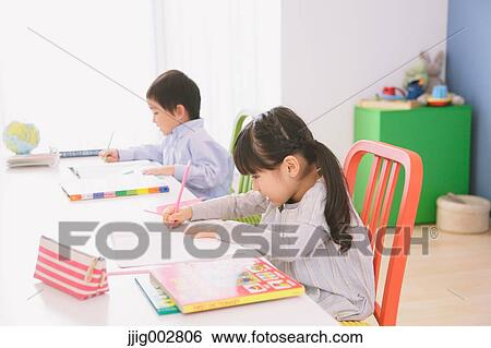Stock Photograph - Elementary age brother and sister doing homework at their desk. Fotosearch