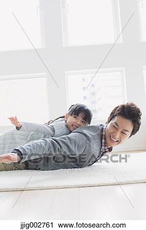 Elementary age girl laying on his fathers back and smiling View Large Photo Image Stock Image - Elementary age girl laying on his fathers back and smiling. Fotosearch
