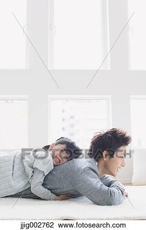 Stock Image - Elementary age girl laying on his fathers back and smiling. Fotosearch