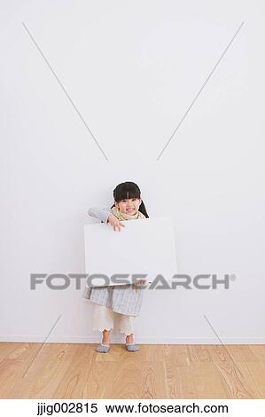 Stock Photography - Elementary age girl leaning against a white wall with whiteboard. Fotosearch