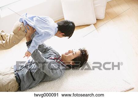 Father laying on the floor and lifting his son while laughing View Large Photo Image Stock Image - Father laying on the floor and lifting his son while laughing. Fotosearch