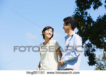 Stock Image - Happy Japanese couple in a park. Fotosearch