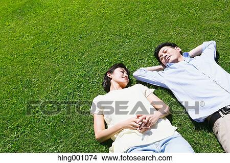 Happy Japanese couple laying on grass in a park View Large Photo Image Picture - Happy Japanese couple laying on grass in a park. Fotosearch