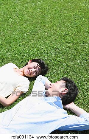Happy Japanese couple laying on grass in a park View Large Photo Image Picture - Happy Japanese couple laying on grass in a park. Fotosearch