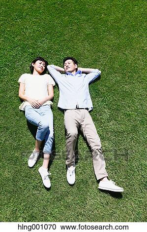 Happy Japanese couple laying on grass in a park View Large Photo Image Stock Image - Happy Japanese couple laying on grass in a park. Fotosearch