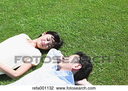 Happy Japanese couple laying on grass in a park View Large Photo Image Stock Image - Happy Japanese couple laying on grass in a park. Fotosearch