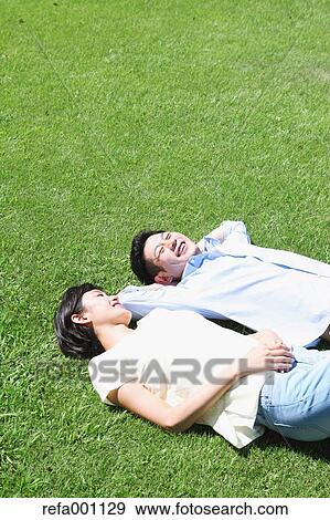 Happy Japanese couple laying on grass in a park View Large Photo Image Stock Photo - Happy Japanese couple laying on grass in a park. Fotosearch