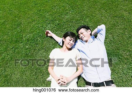 Happy Japanese couple laying on grass in a park View Large Photo Image Stock Photograph - Happy Japanese couple laying on grass in a park. Fotosearch