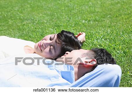 Happy Japanese couple laying on grass in a park View Large Photo Image Stock Photograph - Happy Japanese couple laying on grass in a park. Fotosearch