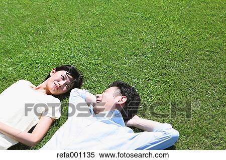 Happy Japanese couple laying on grass in a park View Large Photo Image Stock Photography - Happy Japanese couple laying on grass in a park. Fotosearch