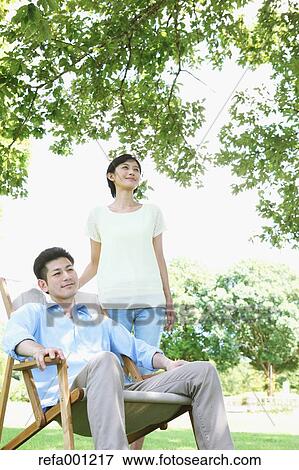 Happy Japanese couple with deck chair in a park View Large Photo Image Stock Photo - Happy Japanese couple with deck chair in a park. Fotosearch