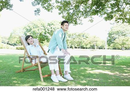 Happy Japanese couple with deck chair in a park View Large Photo Image Stock Photo - Happy Japanese couple with deck chair in a park. Fotosearch