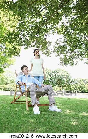 Stock Photograph - Happy Japanese couple with deck chair in a park. Fotosearch