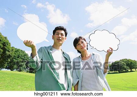 Stock Image - Happy Japanese couple with whiteboards in a city park. Fotosearch