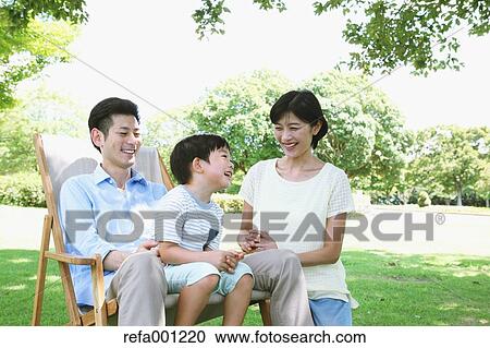 Stock Image - Happy Japanese family in a city park. Fotosearch