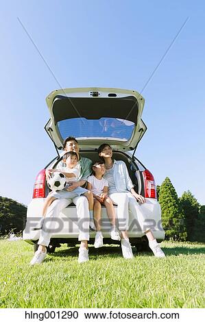 Stock Image - Happy Japanese family with car in a city park. Fotosearch